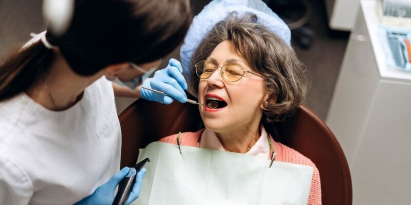 A dentist examining a patient's teeth, highlighting the connection between oral health and overall well-being.