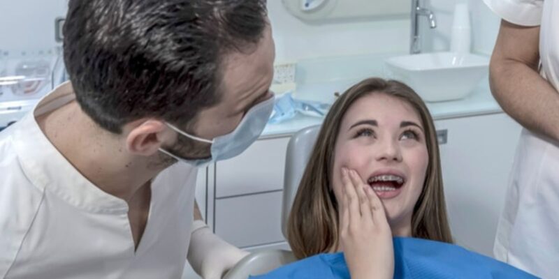 Person with tooth pain holding jaw, seeking dental care in Derry, NH.