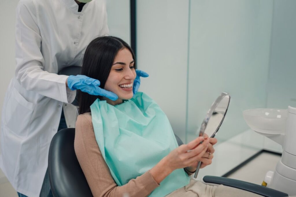 A young woman smiling after cosmetic dental treatment at a clinic.